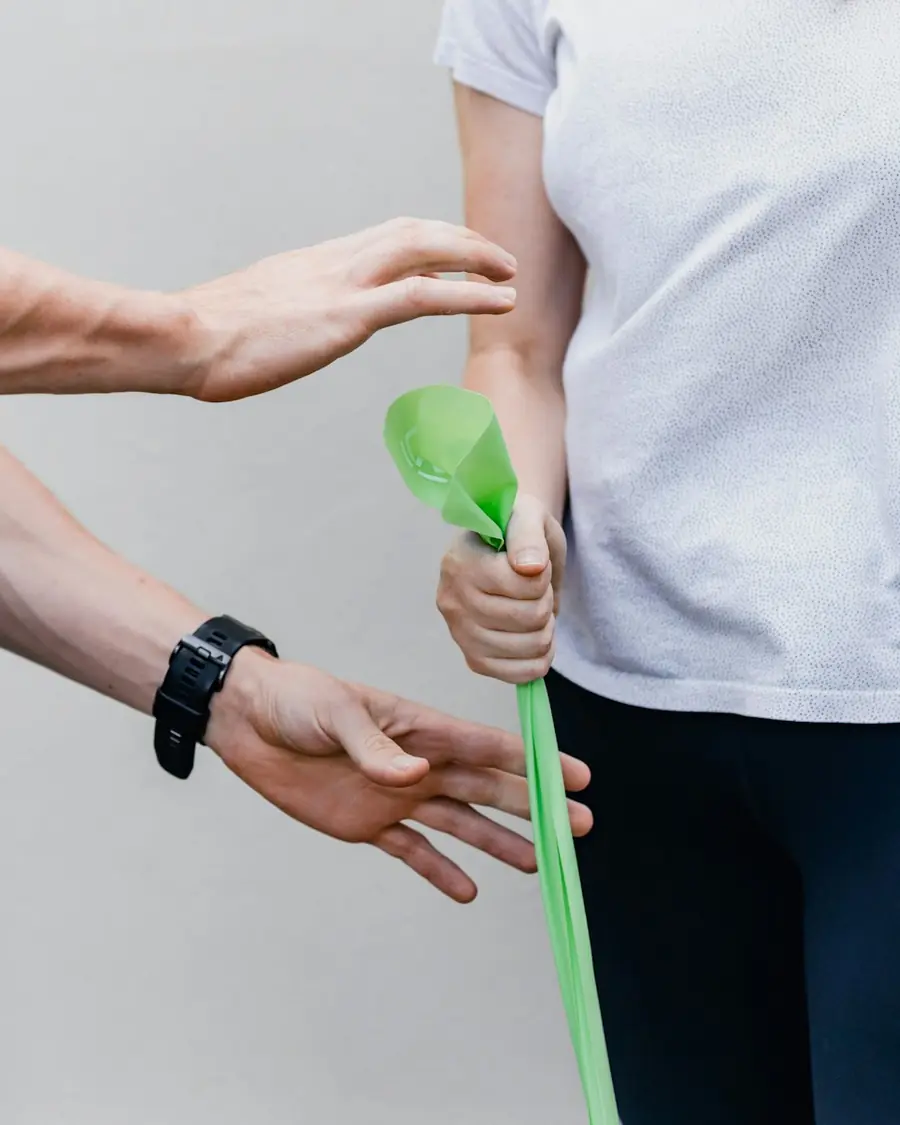 Pacjentka wykonuje ćwiczenie z taśmą pod okiem fizjoterapeuty